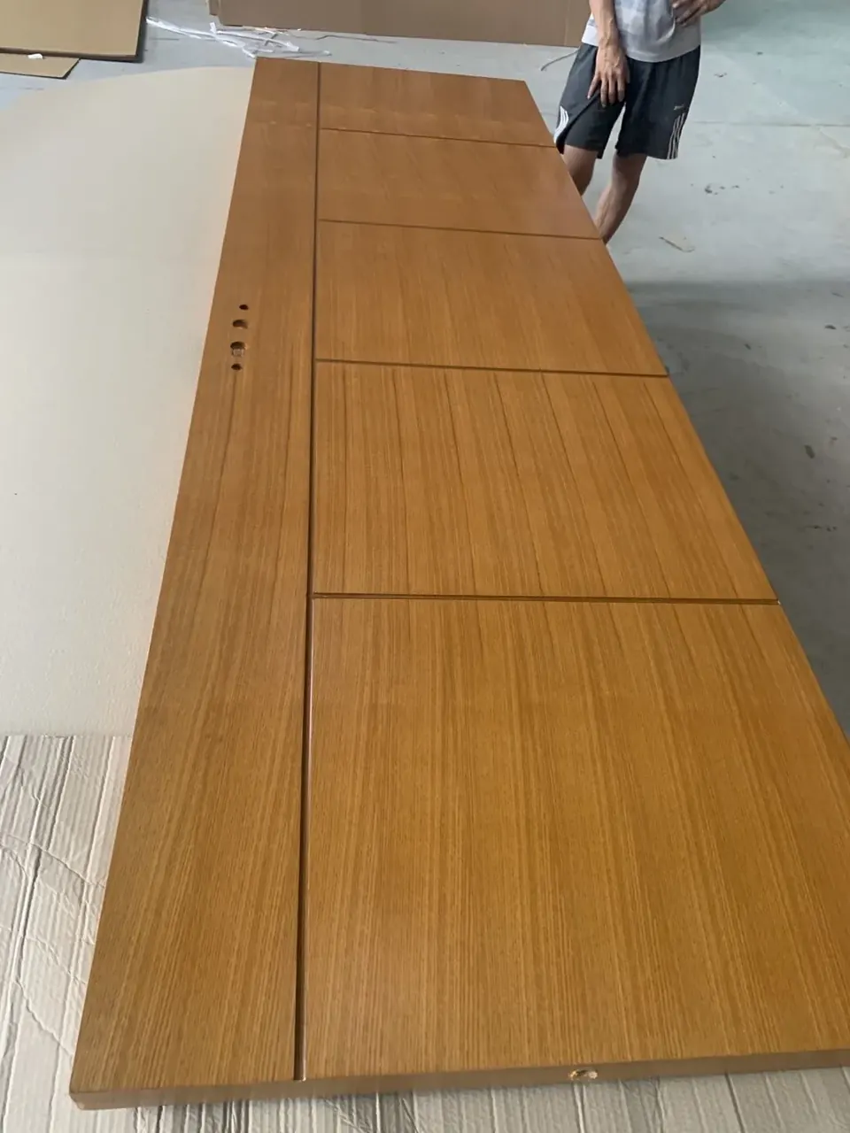 Wood-look interior door leaf with horizontal grooves and handle cutouts on protective cardboard