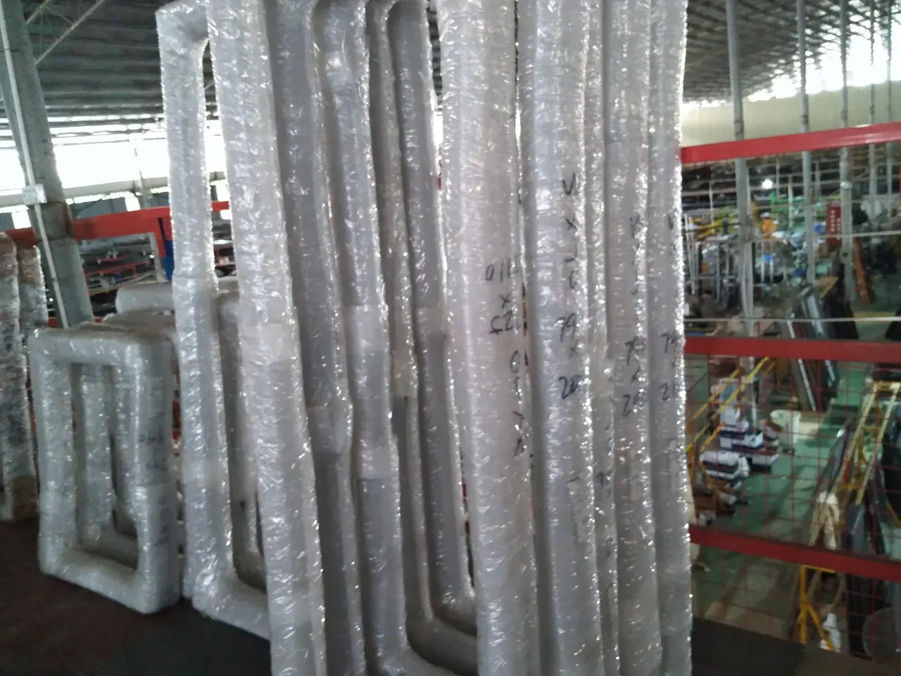 Upright window frames wrapped in protective bubble film inside a workshop