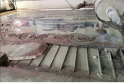 Waterjet cutting head above decorative stone pieces on a machine bed