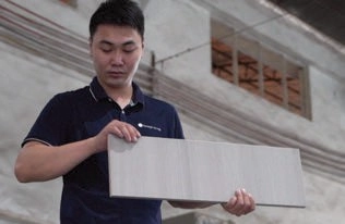 Man inspecting a rectangular light-gray surface panel held in his hands