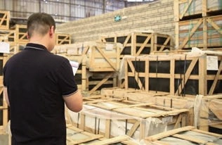 Man standing among stacked wooden shipping crates inside a warehouse