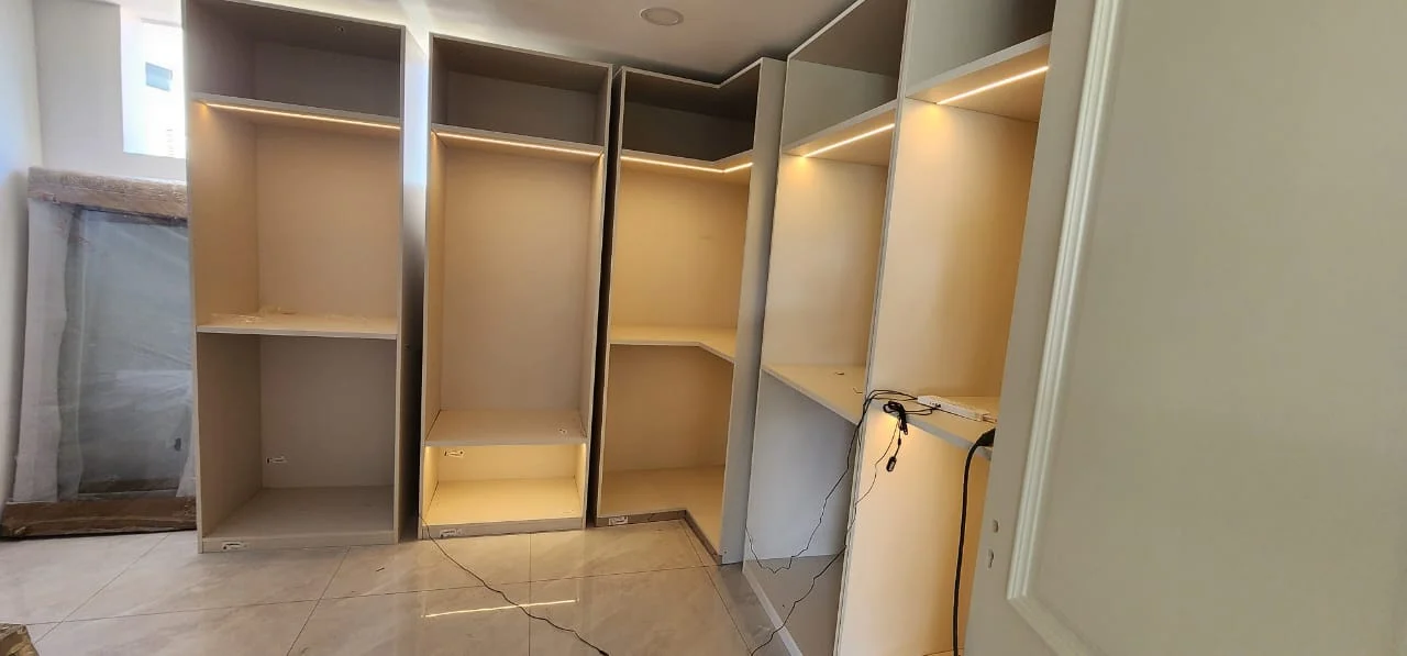 Fitted wardrobe carcasses with internal shelves and lighting during an unfinished installation